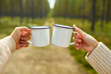 Image showing couple clinking white tea mugs in forest