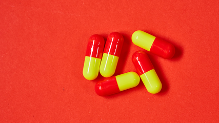 Image showing Pills spilling out of pill bottle on red. Top view with copy space. 