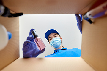 Image showing woman in mask packing parcel box with cosmetics