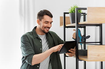 Image showing happy smiling man with tablet pc at shelf at home