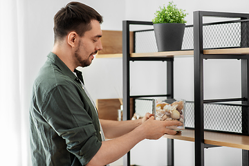 Image showing man decorating home with seashells in vase