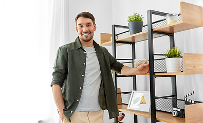 Image showing happy smiling man standing at shelf at home