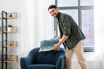 Image showing happy smiling man arranging chair cushion at home