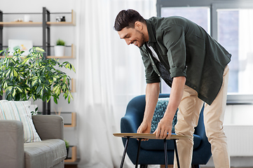 Image showing man placing coffee table next to sofa at home