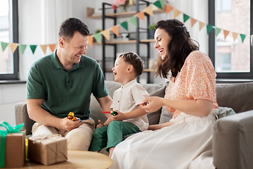 Image showing happy family with gifts and party blowers at home
