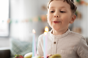 Image showing happy little boy blowing candles on birthday cake