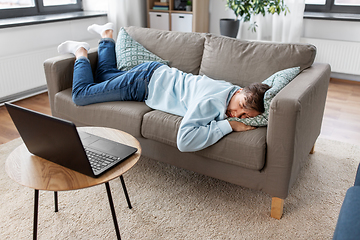 Image showing bored man with laptop lying on sofa at home