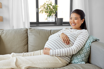 Image showing happy pregnant asian woman sitting on sofa at home