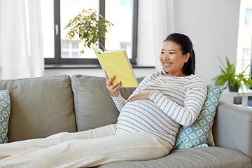 Image showing happy pregnant woman reading book at home