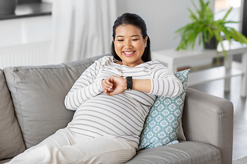 Image showing happy pregnant woman with smart watch at home