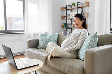 Image showing happy pregnant asian woman with laptop at home