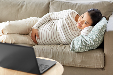 Image showing happy pregnant asian woman with laptop at home