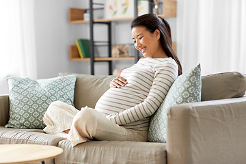 Image showing happy pregnant asian woman sitting on sofa at home