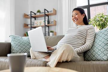 Image showing happy pregnant asian woman with laptop at home