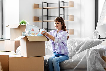 Image showing happy woman unpacking boxes and moving to new home