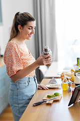 Image showing woman with tablet pc making cocktails at kitchen