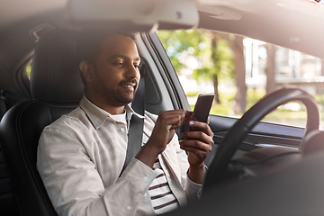 Image showing smiling indian man in car using smartphone