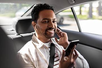 Image showing passenger with earphones and cellphone in taxi car