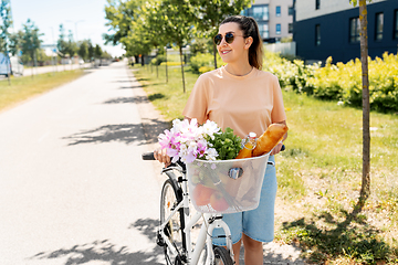 Image showing woman with food and flowers in bicycle basket