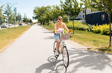 Image showing woman with food and flowers in bicycle basket