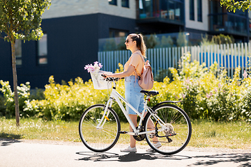 Image showing woman with flowers in bicycle basket in city