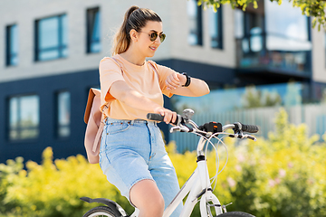 Image showing woman with smart watch riding bicycle in city