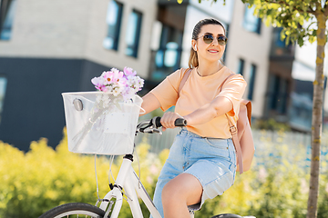 Image showing happy woman with earphones riding bicycle in city