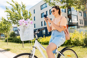 Image showing woman with smartphone on bicycle in city