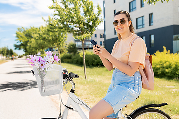 Image showing woman with smartphone on bicycle in city