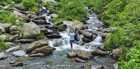 Image showing Woman dpoing yoga asana tree pose at waterfall