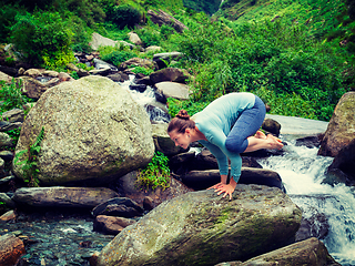 Image showing Woman doing Kakasana asana arm balance at waterfall