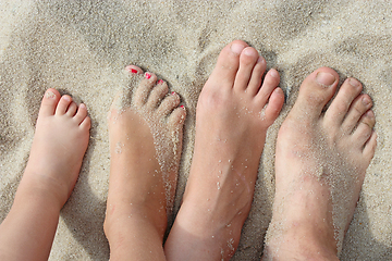 Image showing feet of father mother and their daughters on beach sand