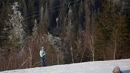 Image showing Happy young woman on button ski lift going uphill