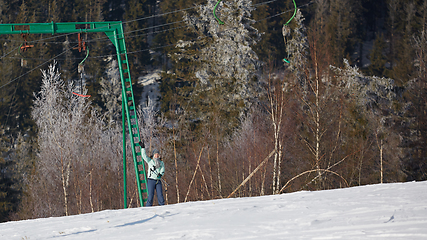 Image showing Happy young woman on button ski lift going uphill