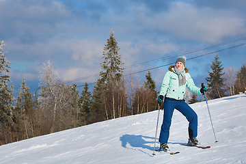 Image showing young beautiful skier rides a ski resort on a background of blue sky