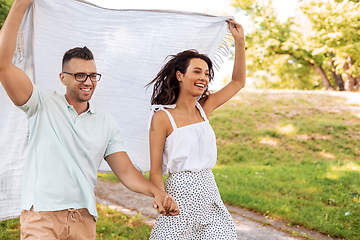 Image showing happy couple with picnic blanket at summer park