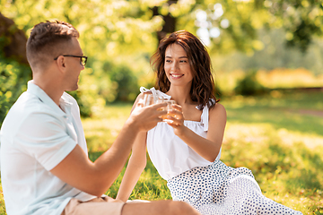 Image showing happy couple toasting drinks at summer park