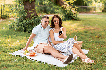 Image showing happy couple with smartphone at picnic in park