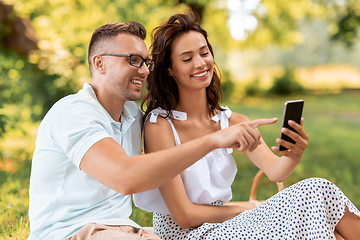 Image showing happy couple with smartphone at picnic in park