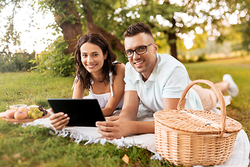 Image showing happy couple with tablet pc at picnic in park