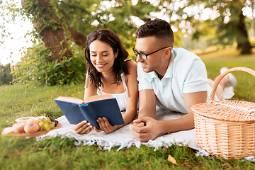 Image showing happy couple reading book on picnic at summer park