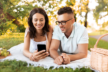 Image showing happy couple with smartphone at picnic in park