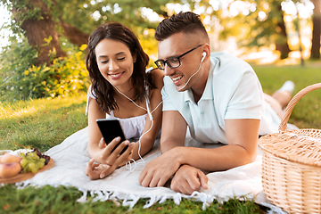 Image showing couple with earphones and smartphone at picnic