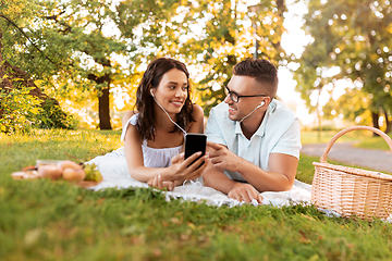 Image showing couple with earphones and smartphone at picnic