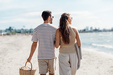 Image showing happy couple with picnic basket walking on beach