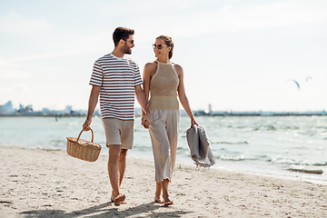 Image showing happy couple with picnic basket walking on beach