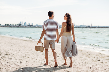 Image showing happy couple with picnic basket walking on beach