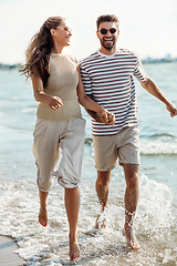 Image showing happy couple running along summer beach