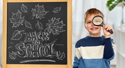 Image showing little student boy looking through magnifier