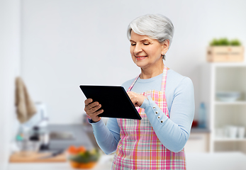 Image showing old senior woman in kitchen apron with tablet pc